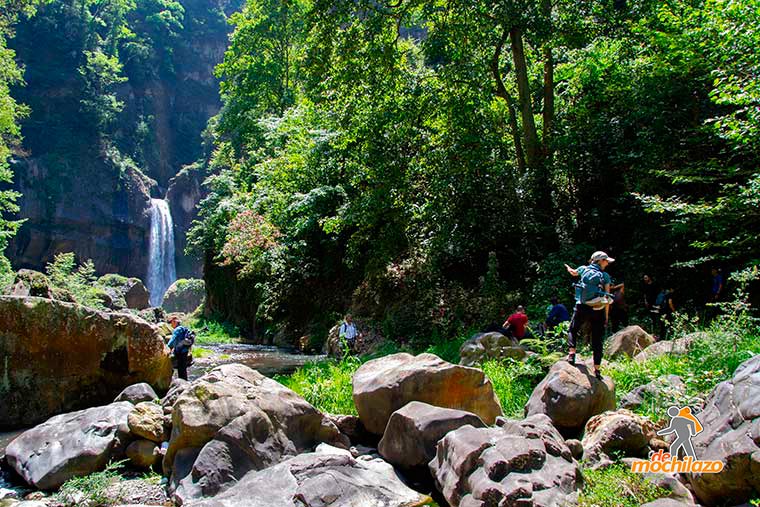 Personas Arriba de una Piedra de fondo la Cascada Salto de Quintanilla Zacapoaxtla De Mochilazo