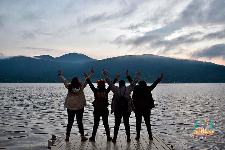 Día de Muertos personas levanando las manos y mirando hacia el lago de Pátzcuaro De Mochilazo